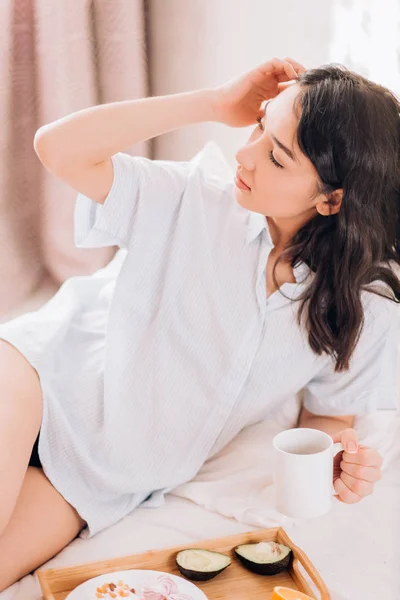 Jovem mulher tomando café da manhã saudável na cama — Fotografia de Stock