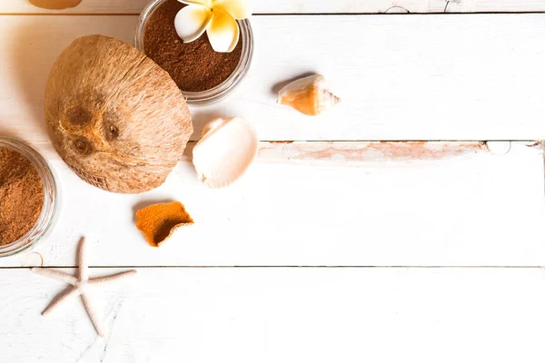 Coconut, spa products, coffee scrub, towels and seashells on white background