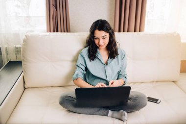 Dizüstü bilgisayar evde kanepede kullanan Bbeautiful kadın