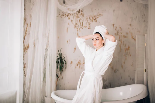 Jolie fille portant un peignoir blanc et une serviette sur la tête dans la salle de bain — Photo