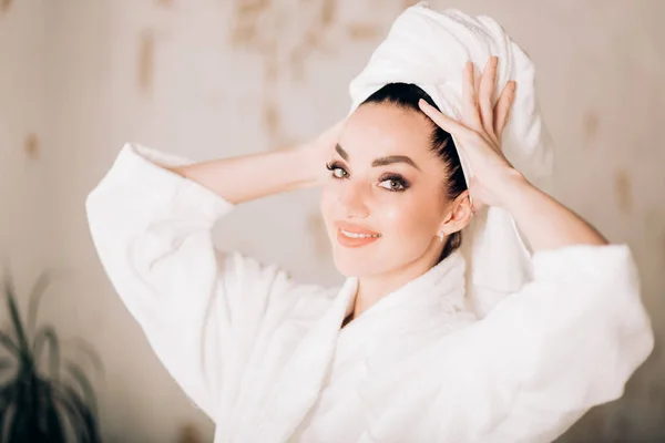 Muchacha atractiva con albornoz blanco y toalla en la cabeza en el baño — Foto de Stock