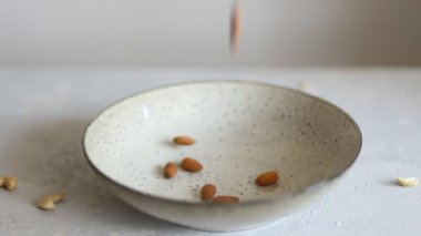 Açık gri bir arka plan üzerinde düşen badem fıstığı büyük bir tabak Closeup