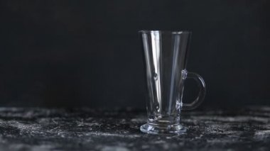 Soda su kabarcıkları sıçrayan, siyah arka planda şeffaf cam bardak içinde damla yüzen. Barmen köpüklü su döker, yakın çekim