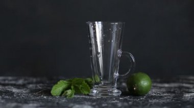 Barmen siyah bir arka plan üzerinde nane ve kireç ile Mojito kokteyl yapmak için gidiyor, köpüklü su şeffaf bir bardak içine döker, closeup. Yaz, serinletici içecekler