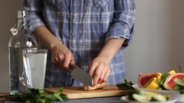 Mutfakta ahşap bir tahta üzerinde bir bıçak ile zencefil kesme bir kadının closeup
