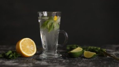 Siyah arka planda nane ve kireç ile Mojito kokteyl. Yaz, serinletici içecekler. Soda su kabarcıkları sıçrama, şeffaf cam bardak içinde yüzen damla