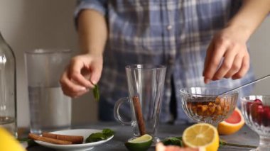 Woman in the kitchen preparing delicious sea buckthorn tea with cinnamon, mint on the table. Food, Haute cuisine