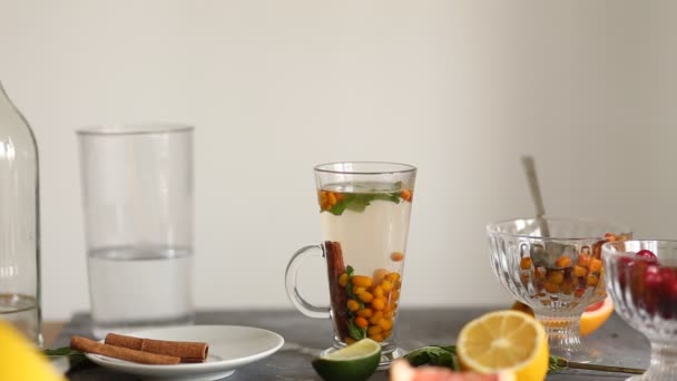 シナモン ミント テーブルの上のライム クローズアップと透明なガラスカップでおいしい熱い海のバックソーンティー — ストック動画
