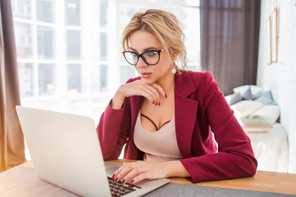 Young female entrepreneur sitting at table in her home office working on laptop
