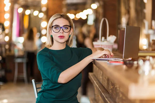 Portrait of pretty young business woman in glasses sitting on workplace