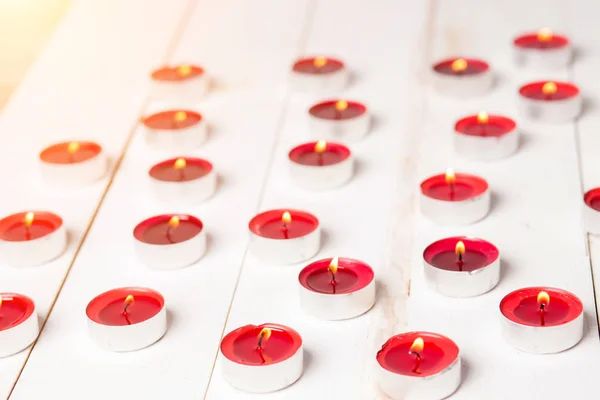 Close-up de pequenas velas vermelhas queimando no fundo de madeira branca — Fotografia de Stock