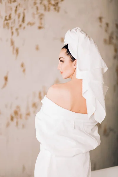 Gadis yang menarik mengenakan jubah mandi putih dan handuk di kepala di kamar mandi — Stok Foto