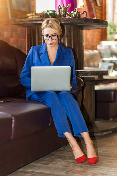 Молода бізнес-леді, що працює онлайн сидячи на дивані — стокове фото