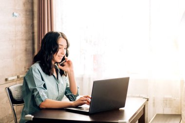 Evde dizüstü bilgisayar kullanan mutlu genç bir kadın.