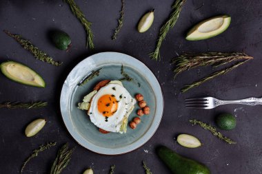 Avokado, biberiye, kireç ile siyah arka plan üzerine üstten görünüm sağlıklı kahvaltı sahanda yumurta ekmek ve bir tabak içinde fındık ile. Üstten Görünüm. Düz yatıyordu. Sağlıklı gıda, beslenme, fitness