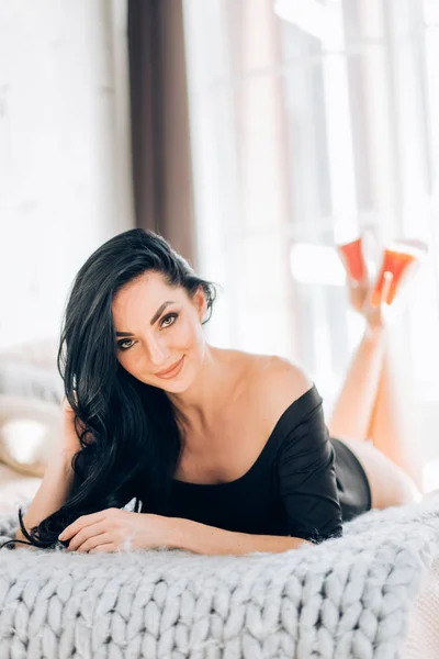 Sexig kvinna klädd i snygga svarta underkläder poserar på sängen i inredningen i lyxiga sovrum — Stockfoto