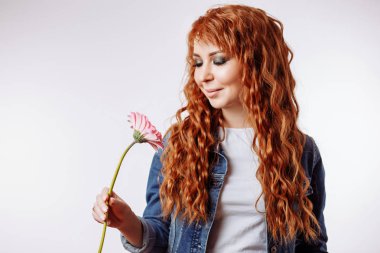 Gülümseyen ve beyaz arka plan üzerinde çiçek tutan oldukça beyaz bir kadın portresi