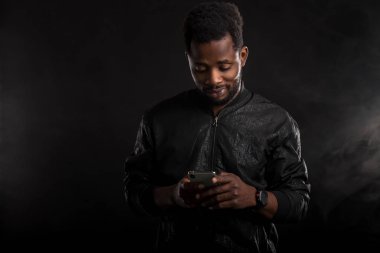 Siyah adam karanlıkta cep telefonu tutan