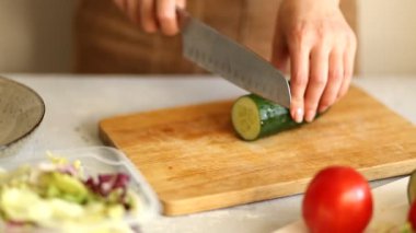 Ahşap bir tahta üzerinde yarım yeşil taze salatalık kadın keser Closeup. Sağlıklı gıda, diyet, Kahvaltı