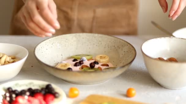 一个女人在早晨在厨房准备一顿美味健康的早餐 手放酸奶浆果 水果和坚果 — 图库视频影像
