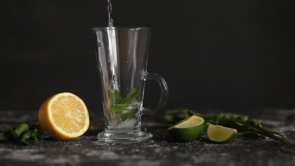 莫吉托鸡尾酒与薄荷和石灰的黑色背景 清凉饮料 苏打水泡飞溅 漂浮在透明玻璃杯中 — 图库视频影像