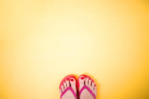 Woman's legs wearing pink flip flops on yellow background with c — ストック写真