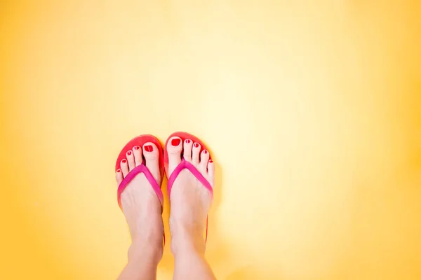 Pernas de mulher vestindo chinelos rosa no fundo amarelo com c — Fotografia de Stock