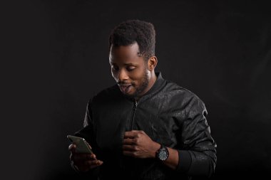 Siyah adam karanlıkta cep telefonu tutan