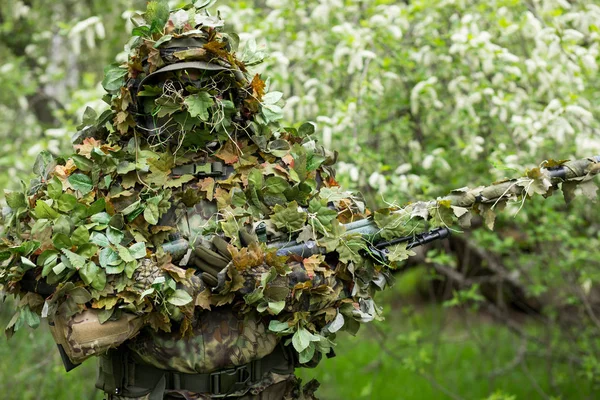 Camouflaged sniper in the forest