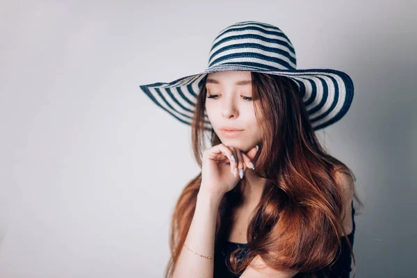 Beautiful woman in hat looking down with a smile on white background. Summer, holiday, sea, copy space, horizontal.