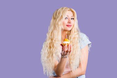 Mutlu güzel kıvırcık genç kadın mum ile doğum günü cupcake tutan