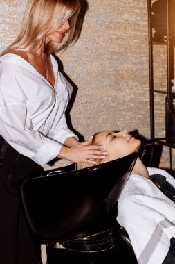 Muhteşem sevimli genç kadın zevk baş şampuan uygulama profesyonel kuaför saçları masajı. İstemcinin kullanabileceği saç yıkama berber el yakın çekim.