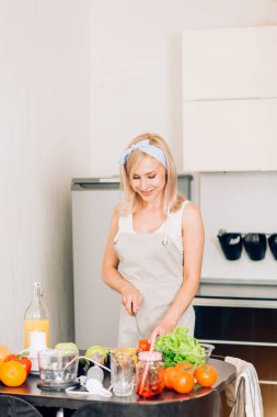 Genç bir kadın mutfakta yemek pişiriyor.