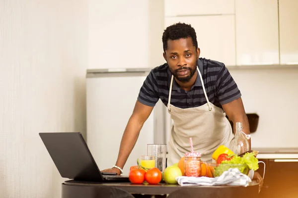Hombre buscando receta en el ordenador portátil en la cocina en casa — Foto de Stock