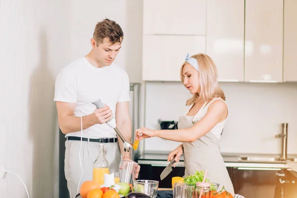 Couple making fresh organic juice in kitchen together — Stock Photo, Image