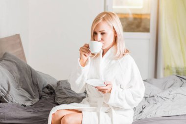 Sabahları yatağında kahve yle dinlenen bornozlu kadın