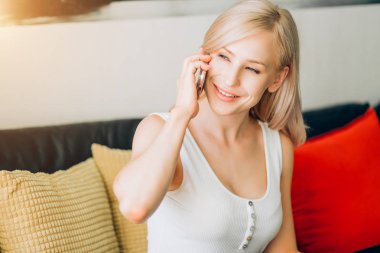 Genç kadın kanepede dinlenirken telefon kullanıyor