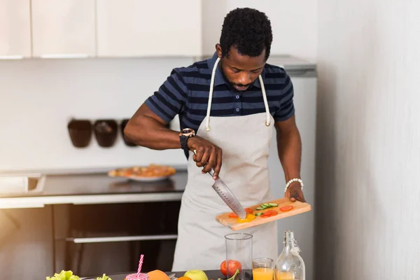 Homem africano preparando comida saudável em casa na cozinha — Fotografia de Stock