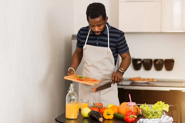 Homem africano preparando comida saudável em casa na cozinha — Fotografia de Stock