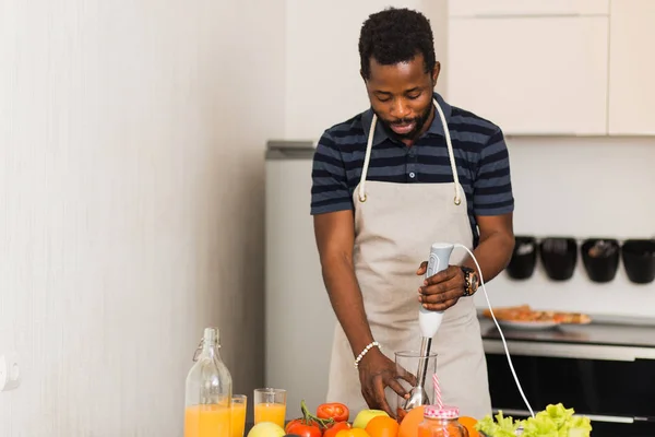 Homem africano preparando comida saudável em casa na cozinha — Fotografia de Stock
