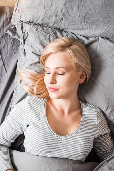 Νεαρή γυναίκα κοιμάται στο κρεβάτι — Φωτογραφία Αρχείου