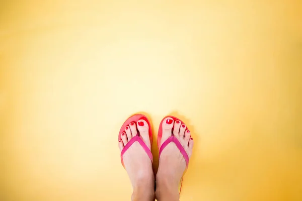 Frauenbeine in rosa Flip-Flops auf gelbem Hintergrund mit Kopierraum — Stockfoto
