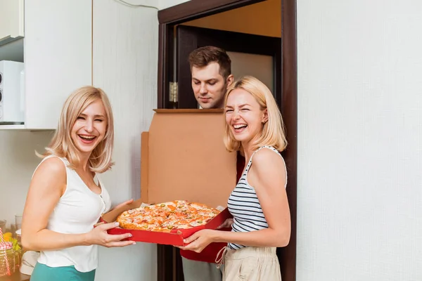 Duas jovens caucasianas recebendo pizza de homem de parto em casa — Fotografia de Stock