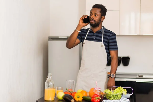 Młody atrakcyjny człowiek rozmawia przez telefon w kuchni — Zdjęcie stockowe