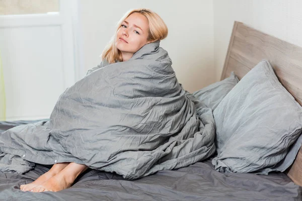 Mulher positiva sentada na cama em casa — Fotografia de Stock