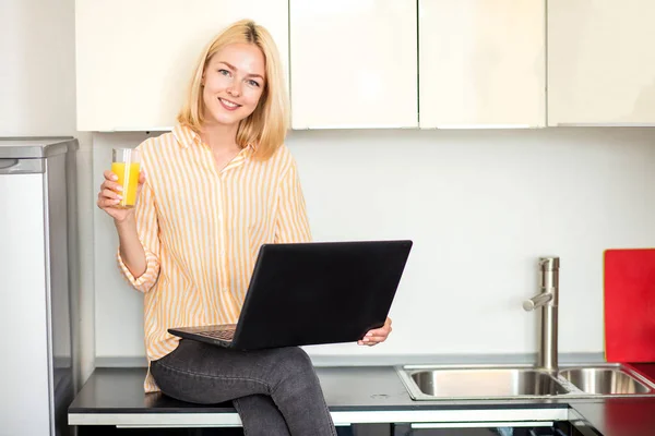 Mulher usando laptop na cozinha — Fotografia de Stock