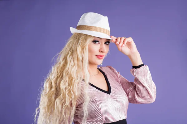 Bella giovane donna in cappello da sole su sfondo viola — Foto Stock