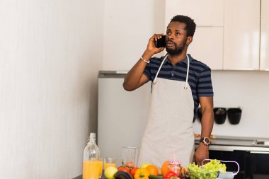 Genç çekici adam mutfakta telefonda konuşurken