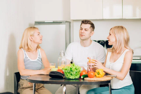 Amigos sentados à mesa na cozinha — Fotografia de Stock