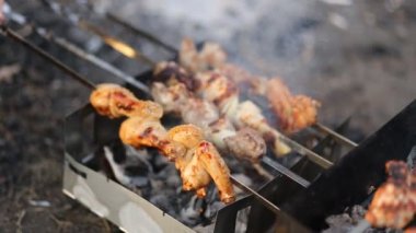 Erkekler tavuk bacaklar ve kanatlar lezzetli pembe kızarmış barbekü pişirmek, doğada et, şişler üzerinde ızgara barbekü açmak, closeup